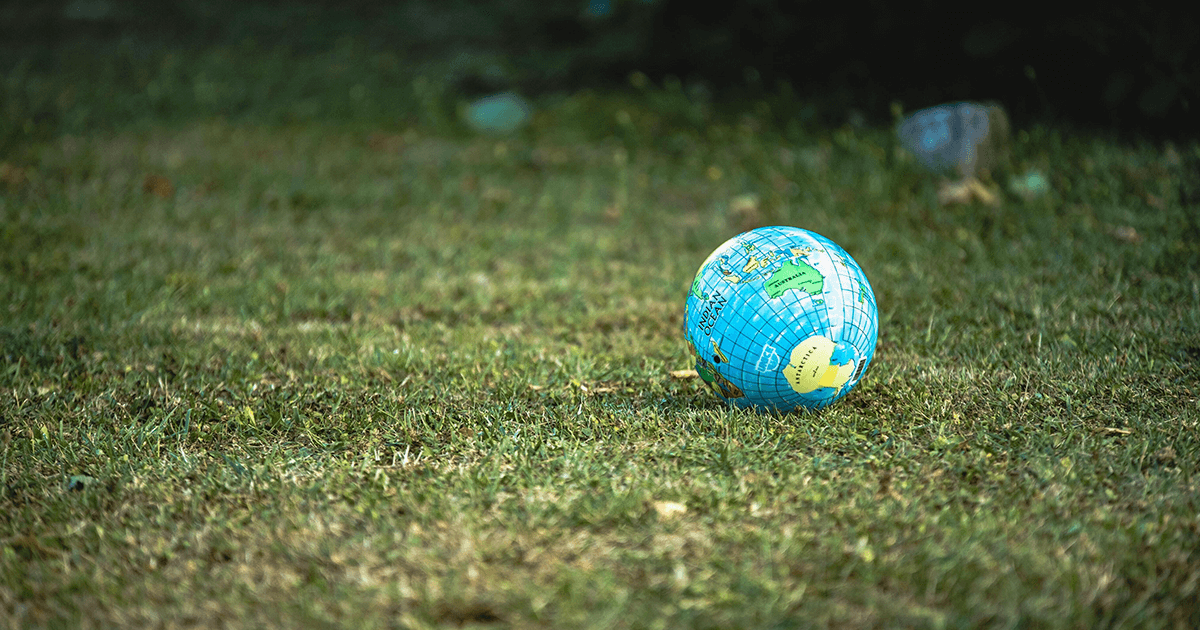 Ballon globe sur une étendue d'herbe verte, symbole du bilan carbone dans le secteur de la publicité